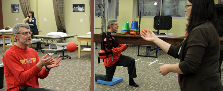 Physical therapist throwing a ball to a patient who is on one knee.